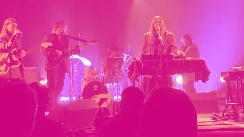 Pink-hued scene of a band performing onstage
